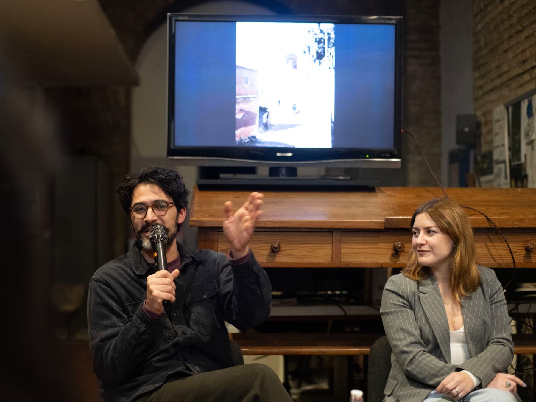 Un relatore al microfono accanto a Ilaria Monti alla presentazione del catalogo di ALCOVE.
